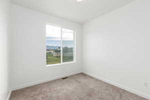 Carpeted spare room featuring baseboards and a mountain view