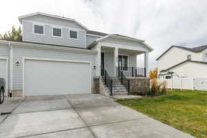 View of front of home with driveway, a porch, and a garage