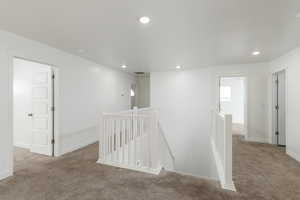 Hall featuring an upstairs landing, light colored carpet, and recessed lighting