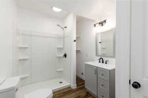 Full bathroom with a stall shower, vanity, and dark wood-style flooring