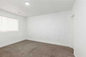 Empty room with dark carpet and baseboards