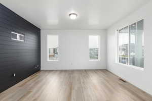 Spare room with wood walls, light wood-style flooring, and an accent wall