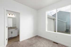Unfurnished bedroom with light colored carpet and ensuite bathroom