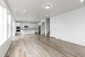 Unfurnished living room with recessed lighting, stairs, and light wood-style flooring