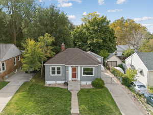 Bungalow-style home featuring a front lawn, roof with shingles, and a chimney