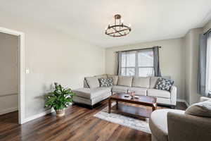 Living area with dark wood-style flooring and a chandelier