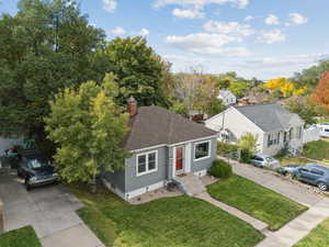 Bungalow with a front yard, a shingled roof, crawl space, and a chimney