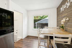 Dining area with wooden walls and dark wood-type flooring