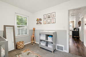Bedroom with multiple windows, dark carpet, a nursery area, and attic access