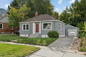 View of front of house featuring an outbuilding, a front yard, entry steps, roof with shingles, and a garage