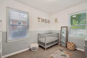 Bedroom featuring carpet flooring, a crib, and a textured wall