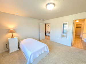 Bedroom with a textured ceiling and light colored carpet