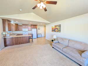 Living room with a ceiling fan, vaulted ceiling, light colored carpet, and recessed lighting