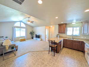Kitchen with a textured ceiling, a kitchen bar, open floor plan, a peninsula, and brown cabinets