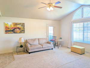 Carpeted living room featuring lofted ceiling, ceiling fan, and a textured ceiling