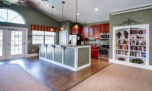 Kitchen with french doors, stainless steel appliances, a breakfast bar area, hanging light fixtures, and dark countertops