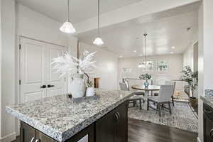 Kitchen with pendant lighting, dark wood finished floors, a center island, dark brown cabinets, and a chandelier