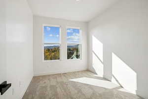 Empty room with light colored carpet and baseboards