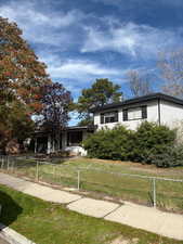 View of front of house with a fenced front yard, covered porch, an attached garage, and driveway