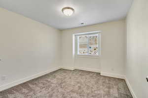Unfurnished room featuring light carpet and baseboards
