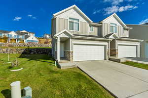 Craftsman house featuring board and batten siding, stone siding, an attached garage, and a front yard