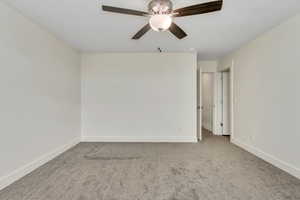 Carpeted empty room with baseboards and ceiling fan