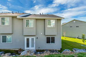 Rear view of house featuring stucco siding and a lawn