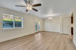 Unfurnished living room with a chandelier, light wood-style flooring, and ceiling fan