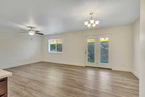 Unfurnished living room with light wood-style flooring, ceiling fan, and a chandelier