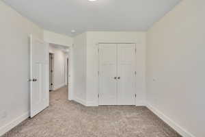 Unfurnished bedroom featuring light carpet and a closet