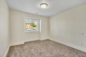 Spare room featuring light colored carpet and baseboards