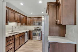 Kitchen with appliances with stainless steel finishes, recessed lighting, light stone counters, and light wood-style floors