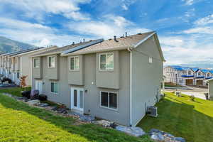 Rear view of house featuring a yard, a mountain view, and stucco siding