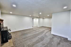 Finished basement featuring light colored carpet, a textured ceiling, and recessed lighting