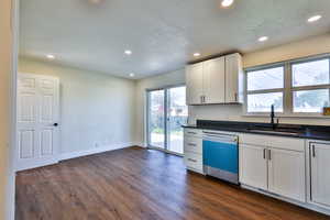 Kitchen featuring recessed lighting, white cabinets, dishwasher, dark wood-style flooring, and dark stone counters