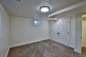 Basement with a textured ceiling and dark carpet