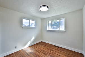 Spare room featuring dark wood finished floors and a textured ceiling