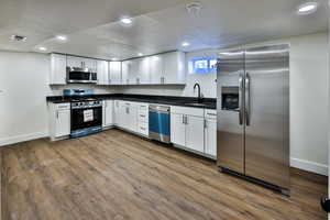 Kitchen with stainless steel appliances, recessed lighting, white cabinets, dark wood-style flooring, and a textured ceiling