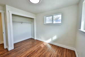 Unfurnished bedroom with dark wood-style floors, a textured ceiling, and a closet