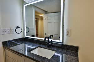 Bathroom with a textured ceiling and vanity