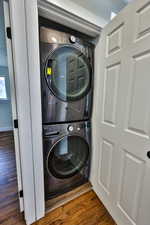 Laundry area with wood finished floors and stacked washer / drying machine