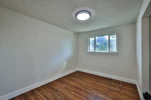 Spare room with dark wood-style flooring and a textured ceiling