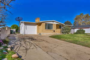 Ranch-style home featuring brick siding, a chimney, concrete driveway, and a garage