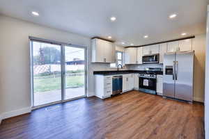 Kitchen with stainless steel appliances, white cabinetry, dark countertops, recessed lighting, and dark wood-type flooring