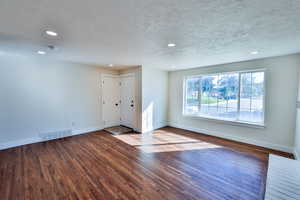 Unfurnished living room featuring recessed lighting, wood finished floors, and a textured ceiling
