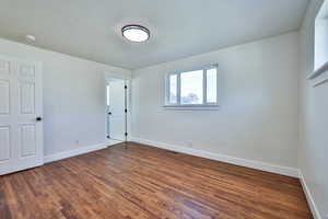 Unfurnished bedroom featuring a textured ceiling and dark wood-style floors