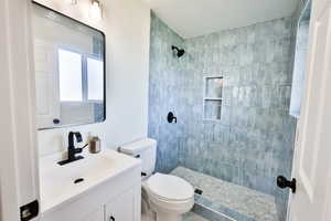 Full bathroom with tiled shower, vanity, and a textured ceiling