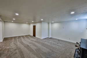 Finished basement with carpet flooring, recessed lighting, and a textured ceiling
