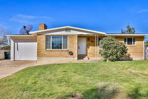Ranch-style home featuring a front lawn, brick siding, concrete driveway, a chimney, and a porch