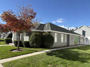 View of front of house featuring a front lawn, a gate, stucco siding, and roof with shingles
